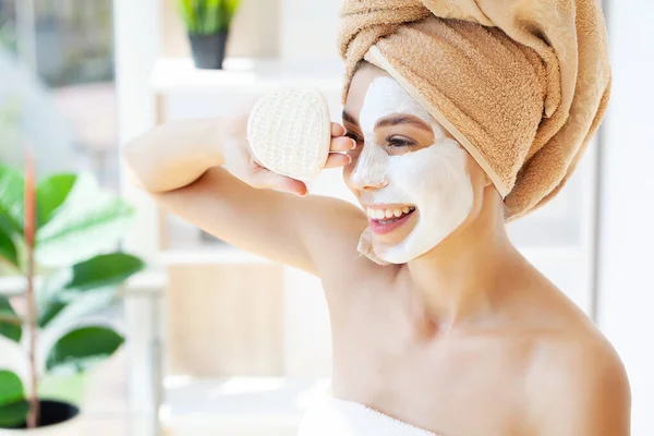 Wanita muda yang bahagia dengan handuk, mengenakan masker tanah liat di kamar mandi bergaya. — Stok Foto