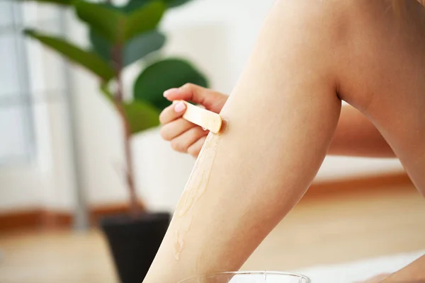 Giovane donna gambe depilanti con zucchero liquido a casa — Foto Stock