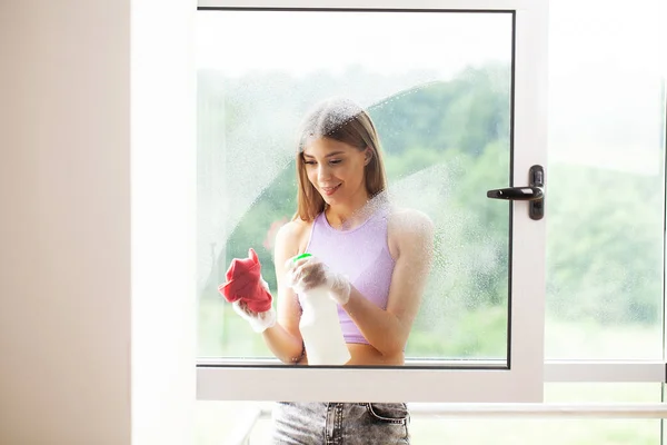Happy young woman housewife washes a window — Stock Photo, Image