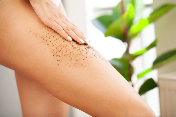 Close-up image of woman massaging feet with coffee scrub
