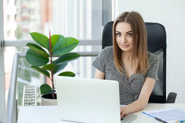 Beautiful business woman is using a laptop and smiling while working in office — Stock Photo, Image