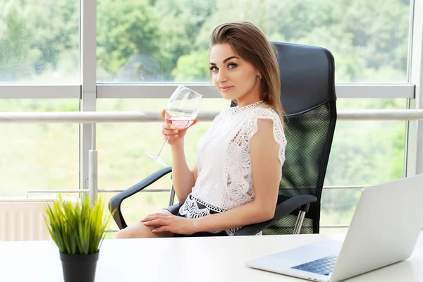 Glad affärskvinna skålar med glas vin på kontoret — Stockfoto