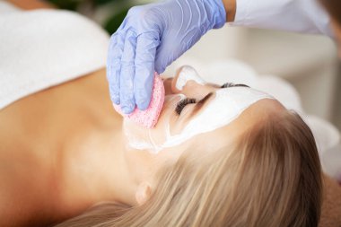 Yüzünde kilden bir maske olan çekici, komik bir kadın..