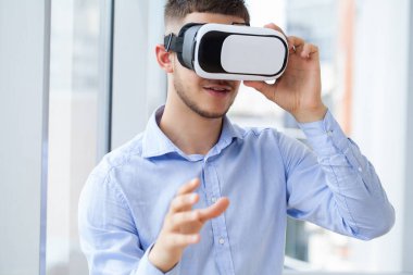 Ofiste VR kulaklık takan genç bir işadamının fotoğrafı.