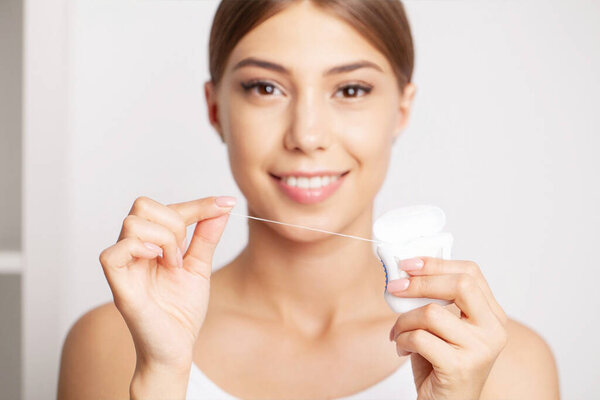 Cleaning teeth with dental floss, perfect healthy tooth