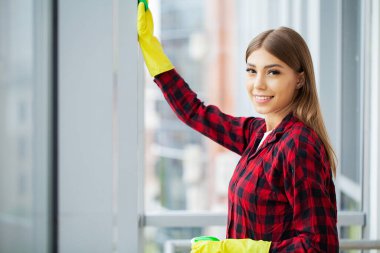 Sarı koruyucu eldivenlerle temizlik yapan genç bir bayan.