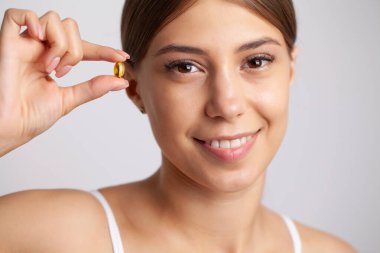 Balık yağı hapını elinde tutan Güzel Kadın.