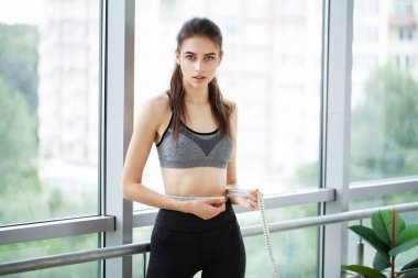 Spor salonunda belini ölçen genç bir kadın..