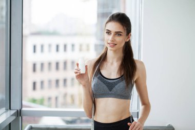 Genç ve güzel bir kadın plastik bir şişe yoğurttan içiyor..