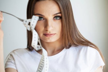 Kadın elleri çatalda beyaz mezura tutuyor..