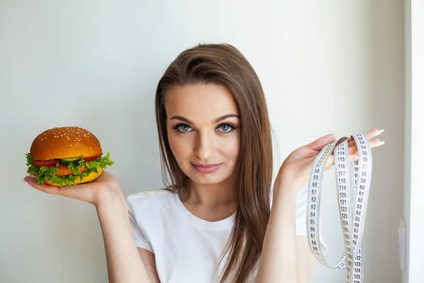 Kobieta Gospodarstwa Szkodliwe Tłuszczu Burger Białą Taśmą Pomiarową — Zdjęcie stockowe