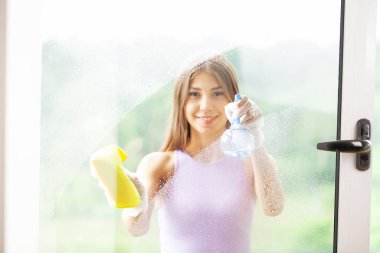 Genç Gülümseyen Kadın Süngerle Pencereyi Siliyor