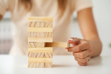 Strateji ve iş sistematik proje yönetimiyle tahta blok oyunu oynayacak genç bir iş kadınının eli.