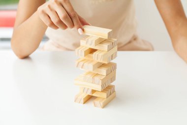 Strateji ve iş sistematik proje yönetimiyle tahta blok oyunu oynayacak genç bir iş kadınının eli.