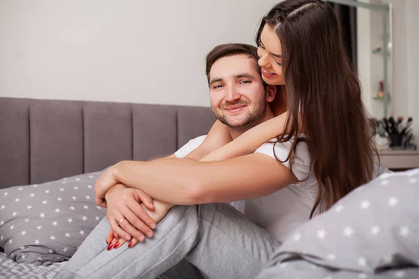 Happy sensual young couple lying in bed together.