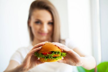 Burger yiyen güzel, aç bir kadının portresi.