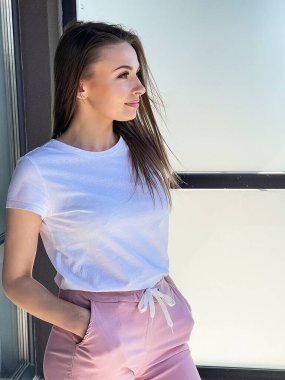 Panoramik pencerenin yanında kalan genç kadın modern evin terasında şehir manzaralı.