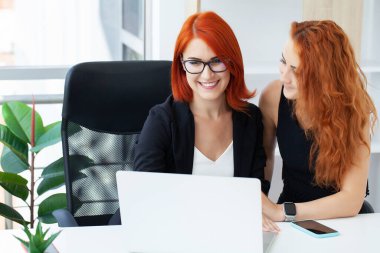 İki kızıl saçlı kadın, ortak bir proje için masadaki ofiste çalışıyor..