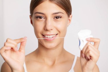 Close-Up diş ipi dişleriyle diş ipi bir kadın.