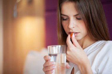 Mutlu kadın bir yatakta evde sabah vitamini hapları.