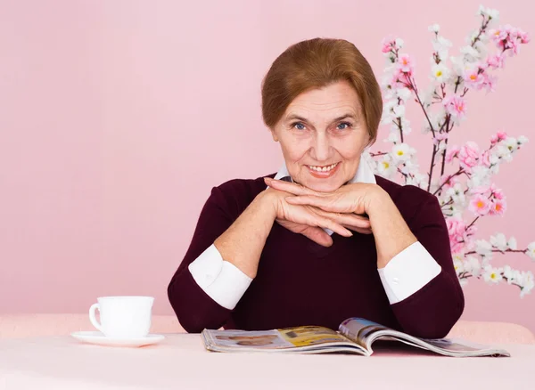 Niza caucásica anciana mujer sentado con una revista —  Fotos de Stock
