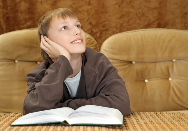 Bellissimo ragazzo caucasico seduto sul divano con un libro — Foto Stock