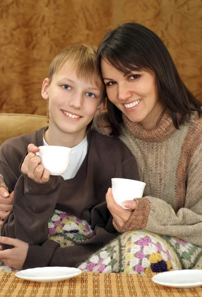Bela mãe e criança sentadas no sofá com um copo — Fotografia de Stock
