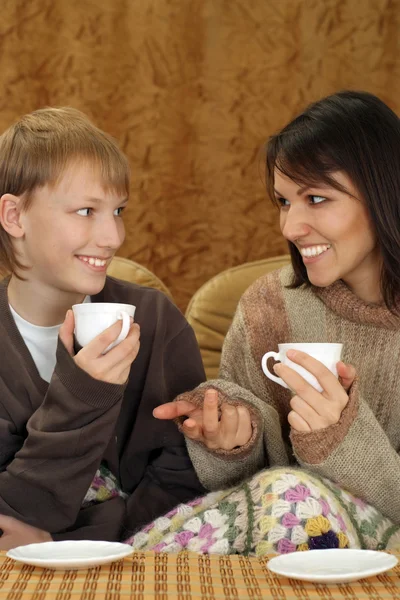 Красивая мать и ребенок сидят на диване с чашкой — стоковое фото