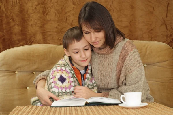 Kanepede oturan oğlu ile güzel bir mutlu anne — Stok fotoğraf