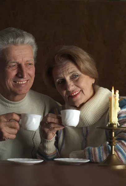 Beautiful Caucasian old couple sitting at a table — Stock Photo, Image