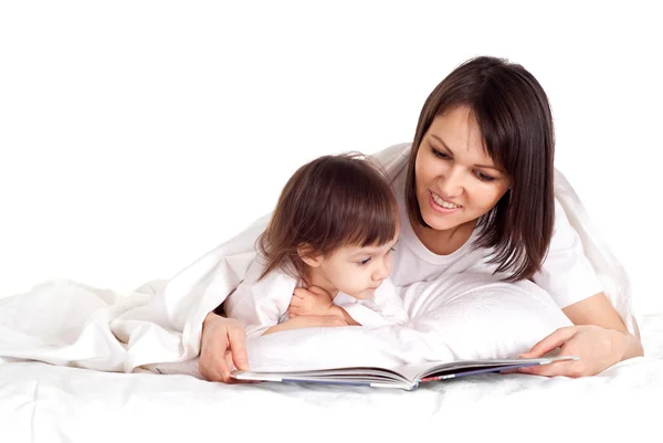 Uma boa mãe caucasiana com sua filha deitada com um livro — Fotografia de Stock