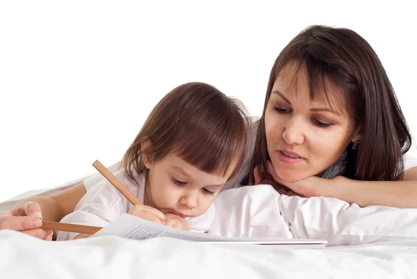 Eine schöne kaukasische Mama mit ihrer Tochter, die mit einem Bleistift lügt — Stockfoto