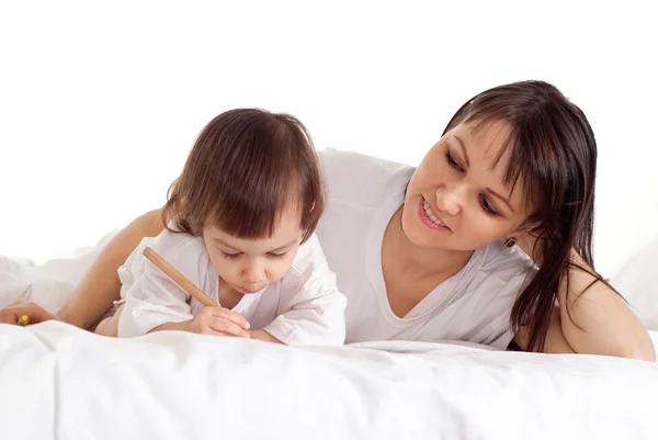 Een goede Kaukasische moeder met haar dochter liggen met een potlood — Stockfoto