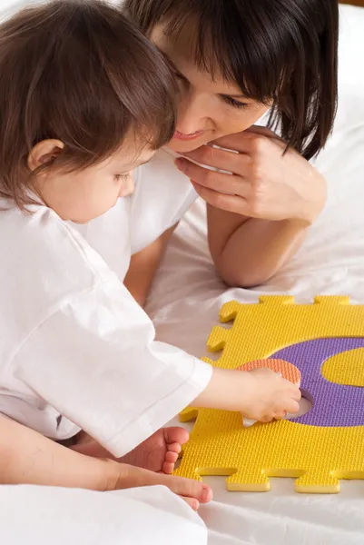 Une belle mère avec sa fille joue avec un tapis — Photo