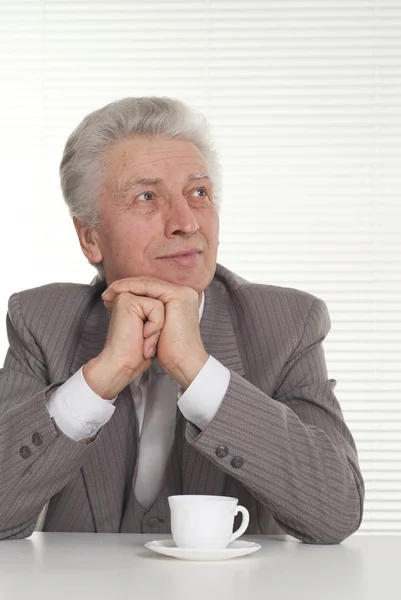 An elderly man with a cup sitting — Stock Photo, Image