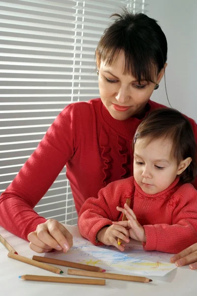 Trevliga kaukasiska glad mamma med en dotter rita med blyerts — Stockfoto