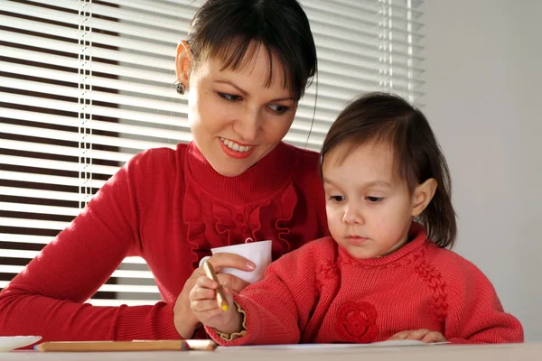 A beautiful Caucasian mother and daughter holding pencils — Stock Photo, Image