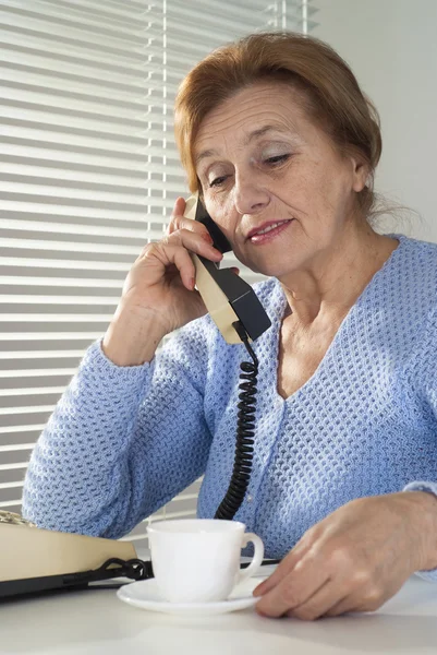 Mulher branca bonita envelhecida com um copo e um telefone — Fotografia de Stock