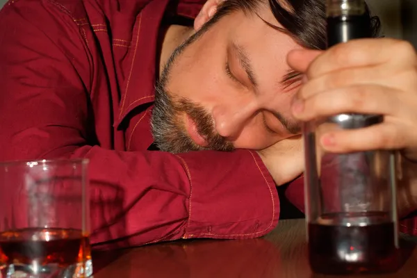 Sleeping man in a red shirt with a bootle — Stock Photo, Image