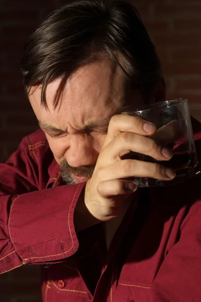 Пьющий человек в красной рубашке — стоковое фото