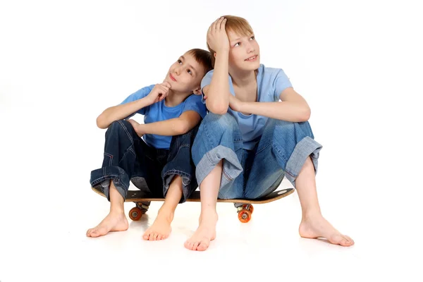 Two boys sitting on a skateboard — Stock Photo, Image
