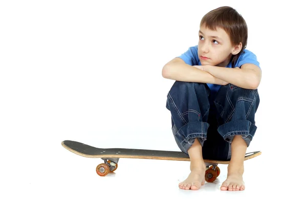 Niño sentado en el monopatín — Foto de Stock