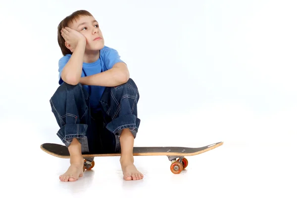 Chlapec sedí na skateboardu — Stock fotografie