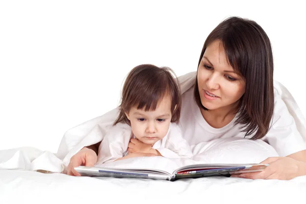 Una madre caucásica feliz con su hija acostada con un libro Fotos de stock