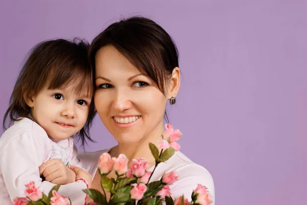 Mulher caucasiana feliz com uma filha e flores — Fotografia de Stock