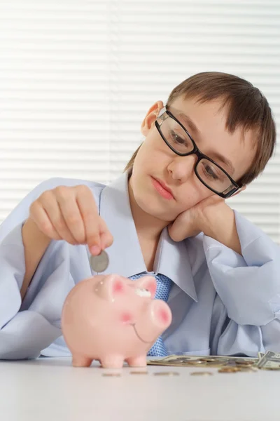 Jonge Kaukasische bedrijf een aardige vent zet een munt in een piggy bank — Stockfoto