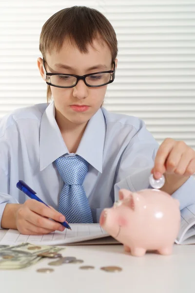 Jonge Kaukasische bedrijf een gelukkig man zet een munt in een piggy bank — Stockfoto