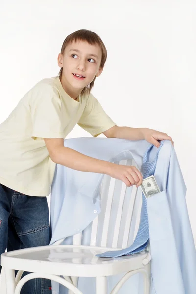 Knappe jongen krijgt geld van de shirts opknoping op een stoel — Stockfoto