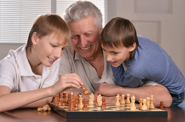 Два мальчика и дедушка играют в шахматы — стоковое фото