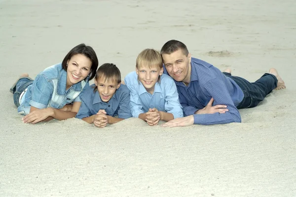 Семья, лежащая на песке — стоковое фото